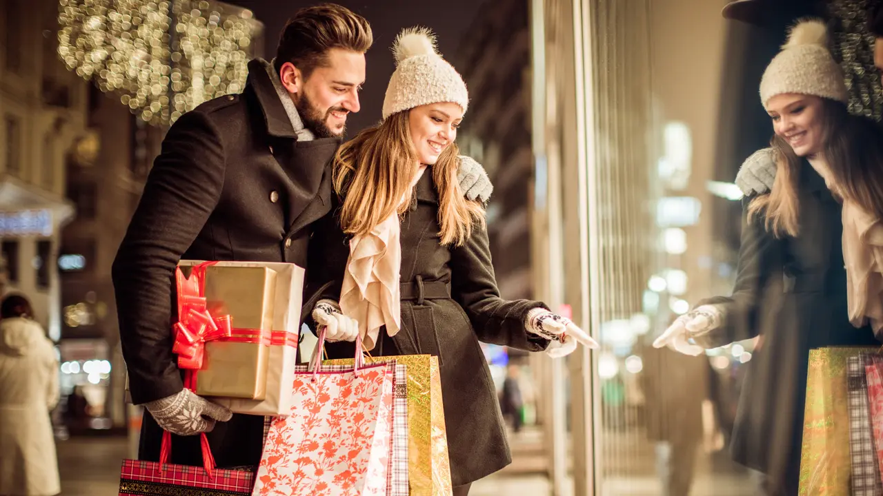 Couple window shopping outdoors in winter city street.