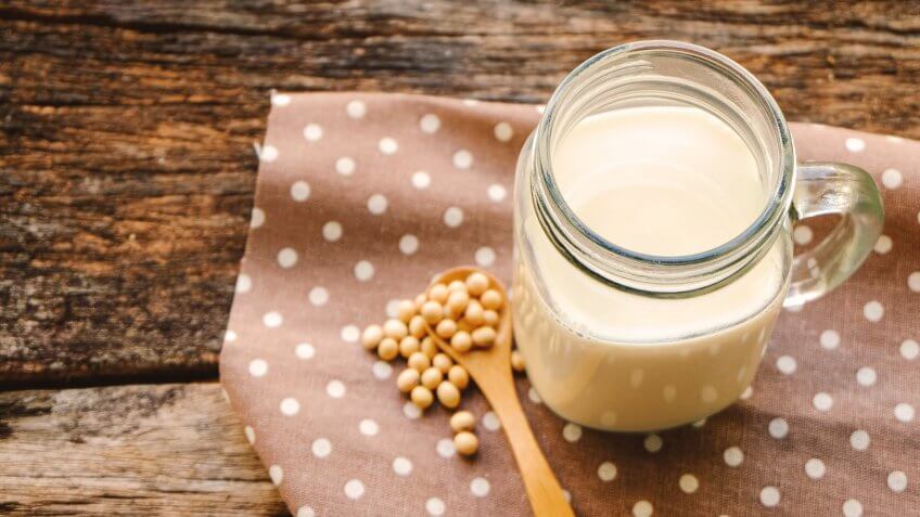 organic homemade soy milk in glass and soy bean on wood table background.