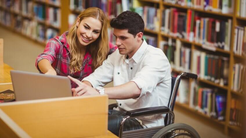 Student in wheelchair working with a classmate in library.