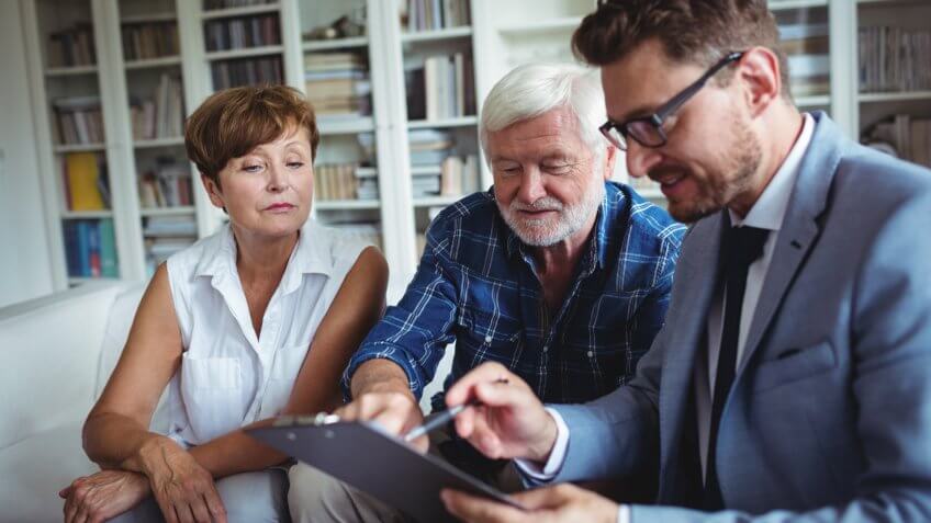 Senior couple planning their investments with financial advisor in living room.