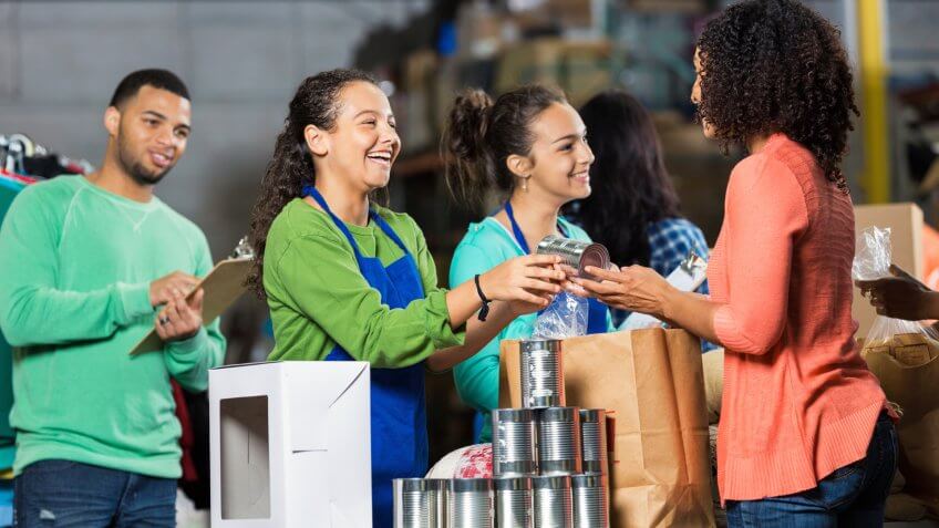 Diverse volunteers happily received canned goods and other items from woman.