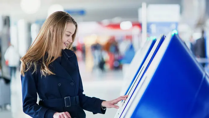 Young woman in international airport doing self check-in.
