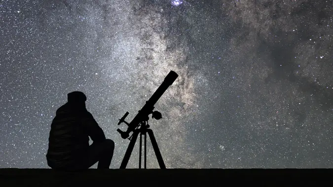 Man with astronomy telescope looking at the stars.