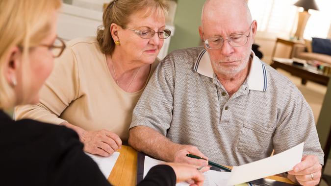 Senior adult couple goes over papers in their home with agent.