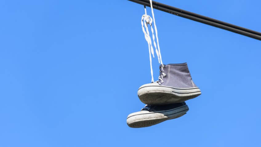 A pair of blue high converse sneakers suspended on a stick.