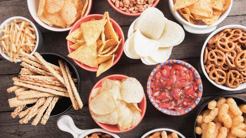 Salty crackers, tortilla chips and other savory snacks with salsa dip.