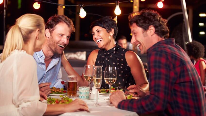 Group of friends eating dinner at rooftop restaurant.