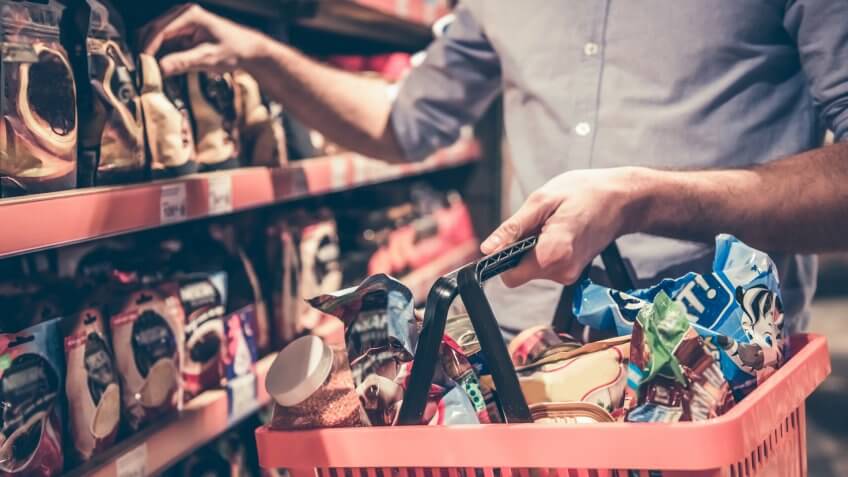 Cropped image of handsome man with a market basket doing shopping at the supermarket.