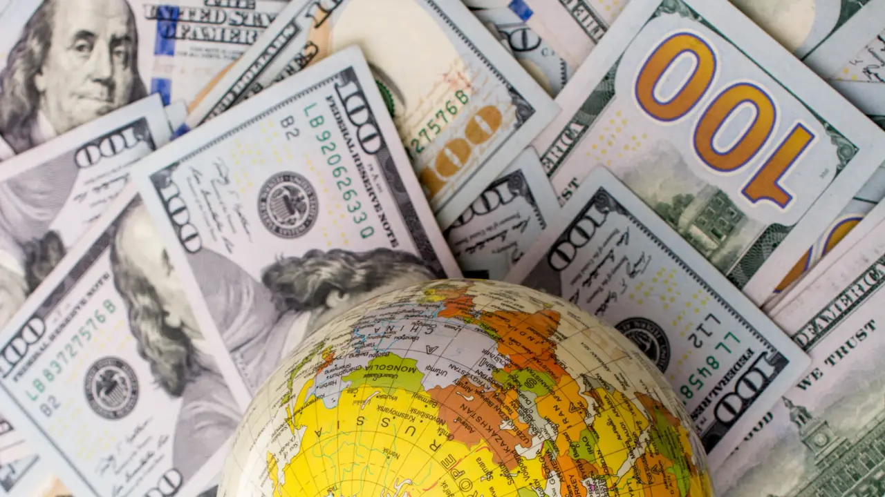 Model globe is placed on spread US dollar banknotes.