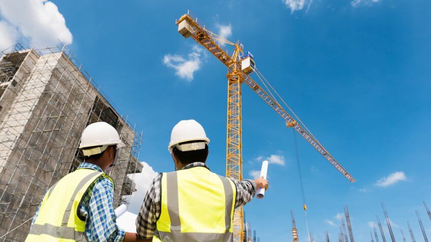 People in construction hats looking up at crane