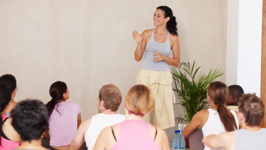A group of people sitting on their exercise mats and listening to their yoga instructorhttp://195.