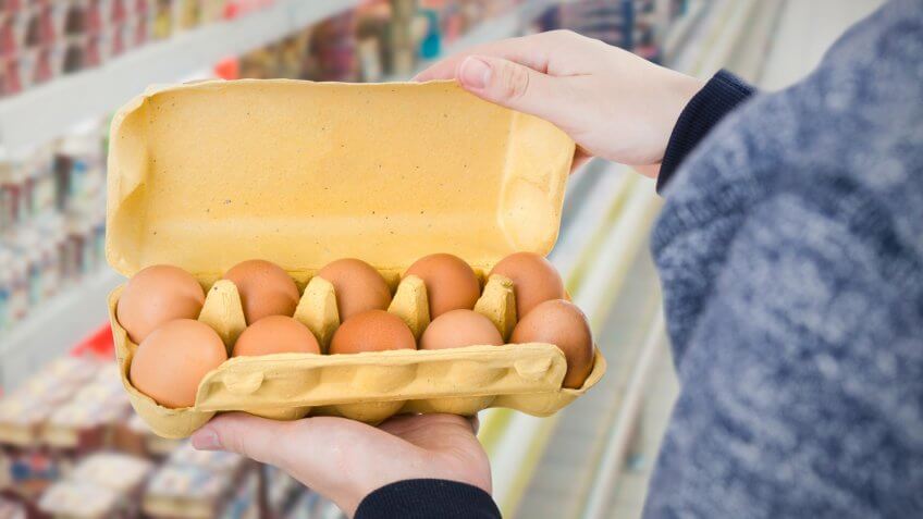Man holding egg box in supermarket.