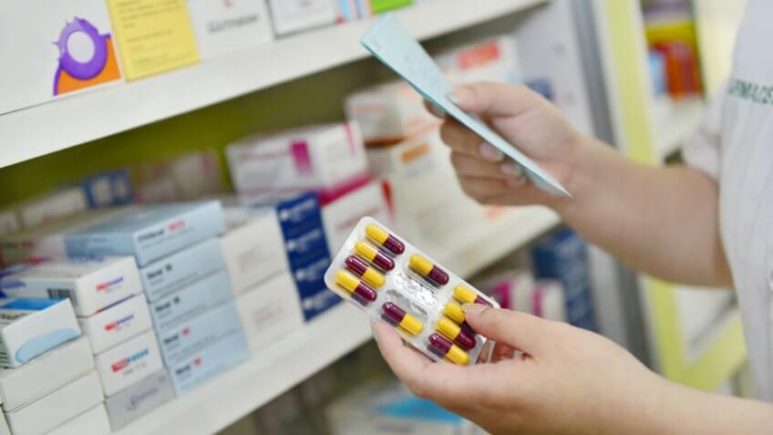 Hand holding medicine capsule pack at the pharmacy drugstore.