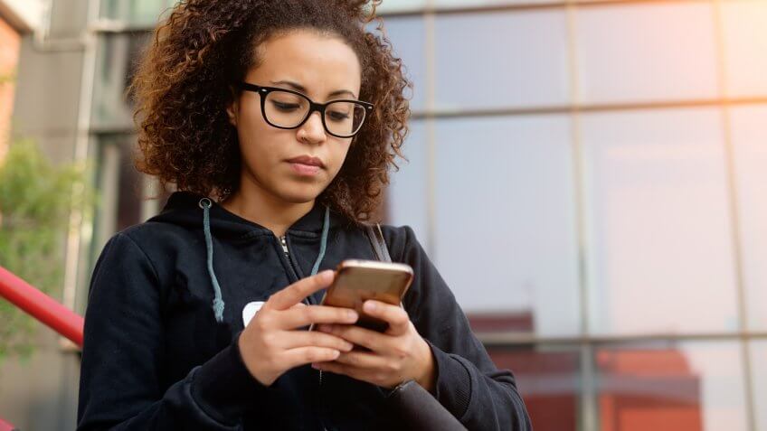 Young millenial girl texting on her mobile phone.