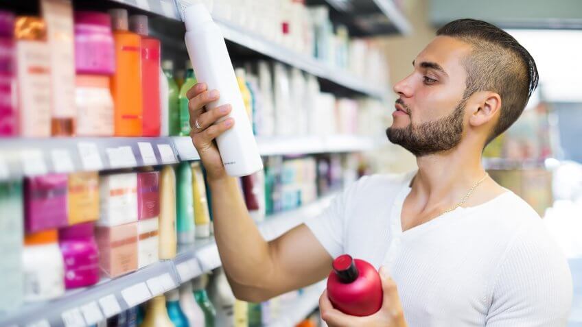 Attractive man buying shampoo in shopping mall.