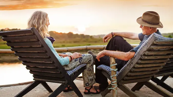 A couple sitting in lounge chairs during a sunset.