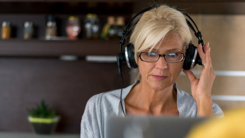 Senior woman listening to the music while surfing the net at home.