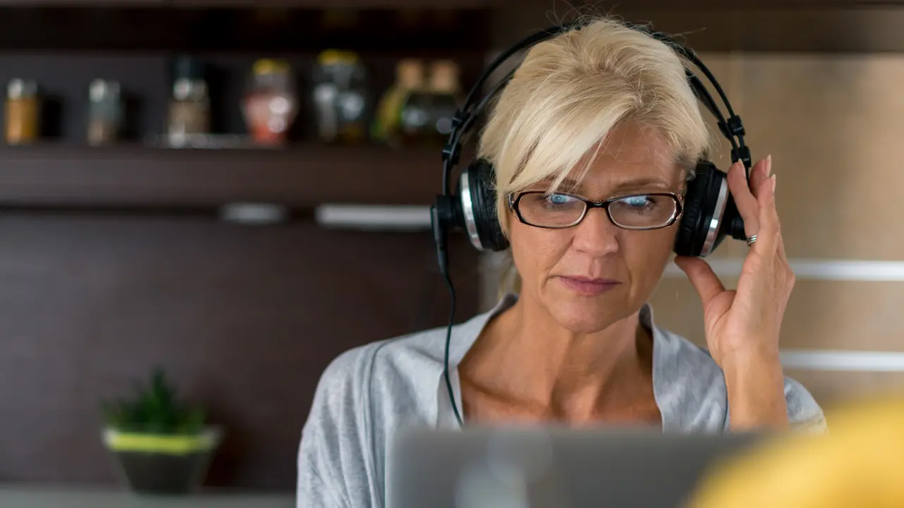 Senior woman listening to the music while surfing the net at home.