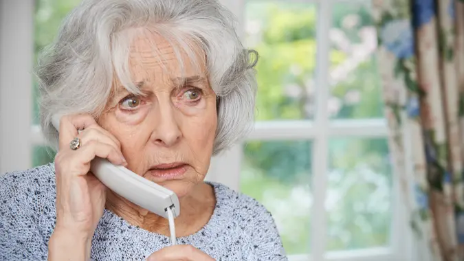 Worried Senior Woman Answering Telephone At Home