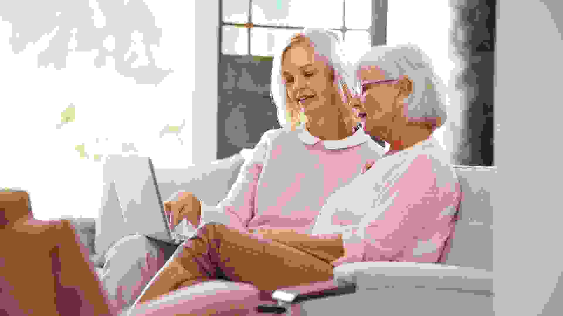 Daughter Helping Senior Mother With Computer At Home