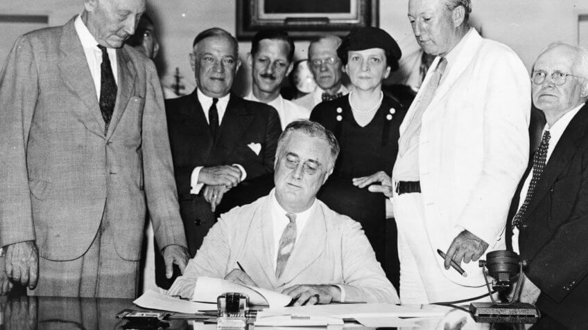 Roosevelt signs Social Security Bill.