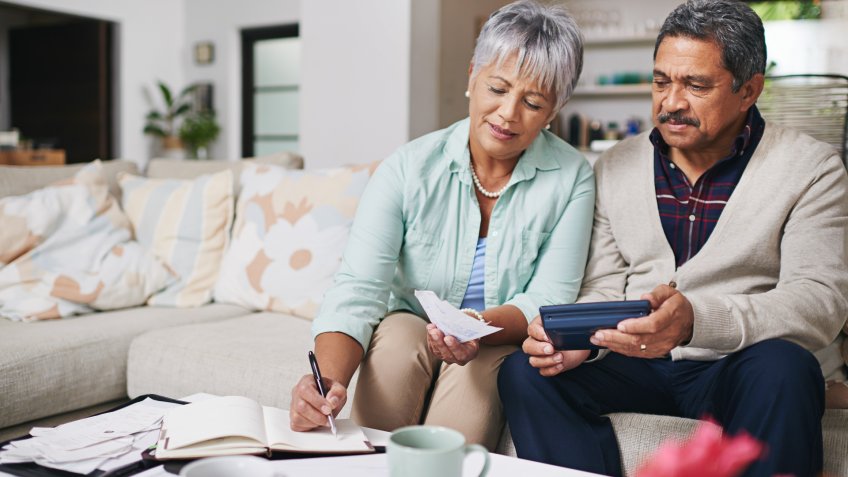 elderly couple working out a budget while sitting on the living room sofa