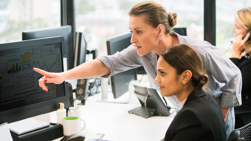 Businesswomen working together at computer workstation.