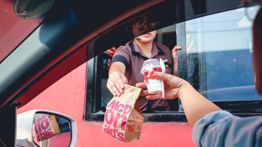Bangkok, Thailand - Mar 4, 2017: Unidentified customer receiving hamburger and ice cream after order and buy it from McDonald's drive thru service, McDonald's is an American fast food restaurant chain.
