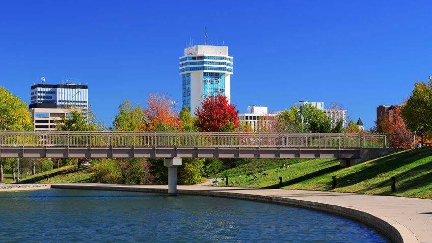Downtown Wichita skyline with a waterway and park in the foreground.