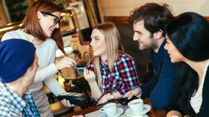 millennial group of friends getting coffee and using credit card