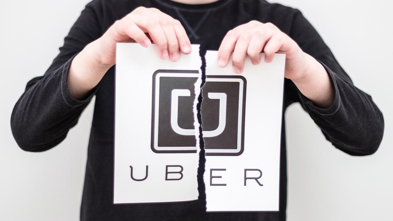Minsk, Belarus - March 11, 2017: Boy breaks the logo of the world famous social service Uber, printed on paper.