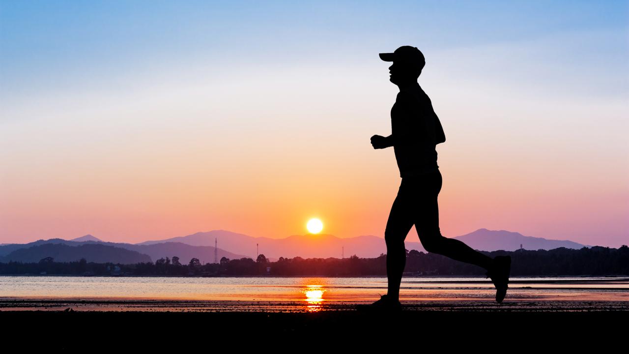 silhouette of man running on beach at sunset or sunrise
