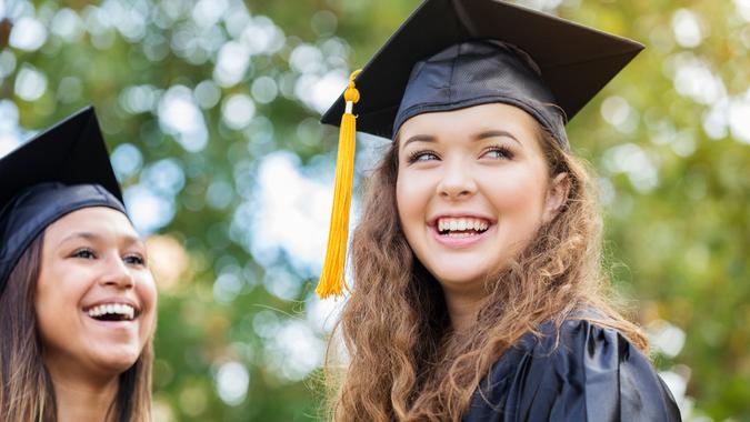 College graduate smiles confidently outdoors after graduation ceremony.