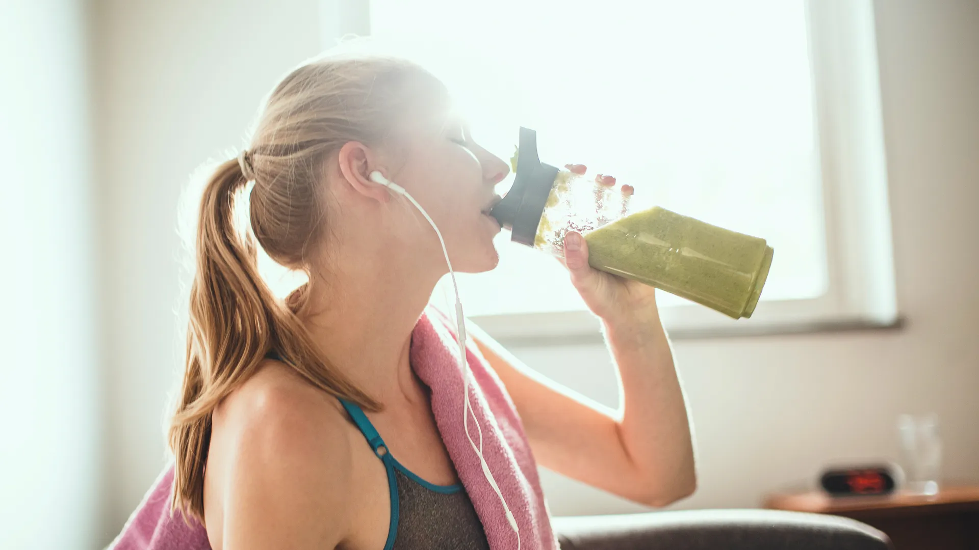 Young woman getting having her green smoothie after training.