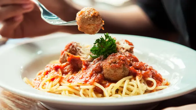 close up of woman eating spaghetti meatball.