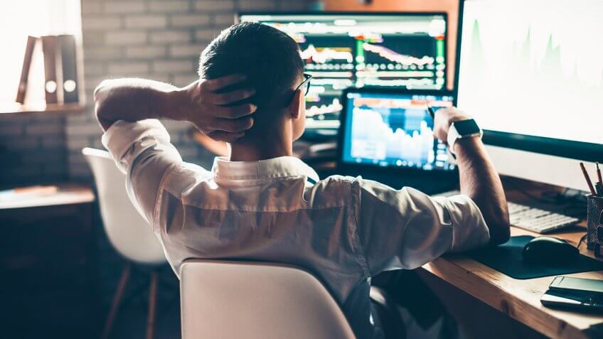 man checking stocks on computer monitors at desk