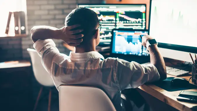 man checking stocks on computer monitors at desk