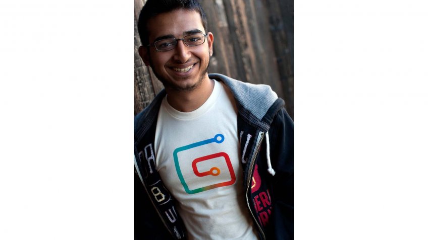 Sahil Lavingia in front of wood, wearing Gumroad shirt.