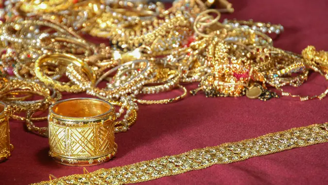 Gold jewelry laid out on a red fabric to show wealth, potential money gains and more.
