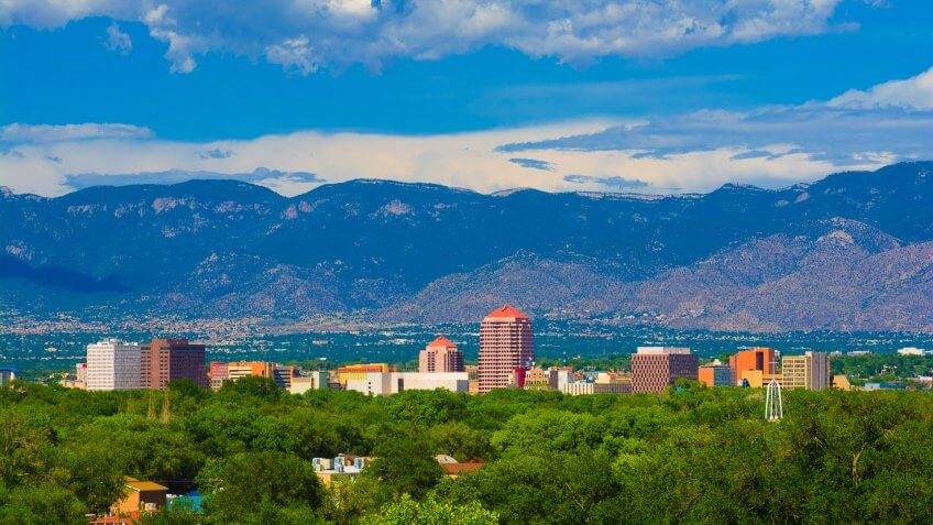 Albuquerque downtown skyline with the Sandia Mountains and clouds in the background.