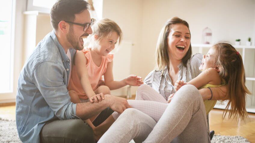 Happy family with two daughters playing at home.