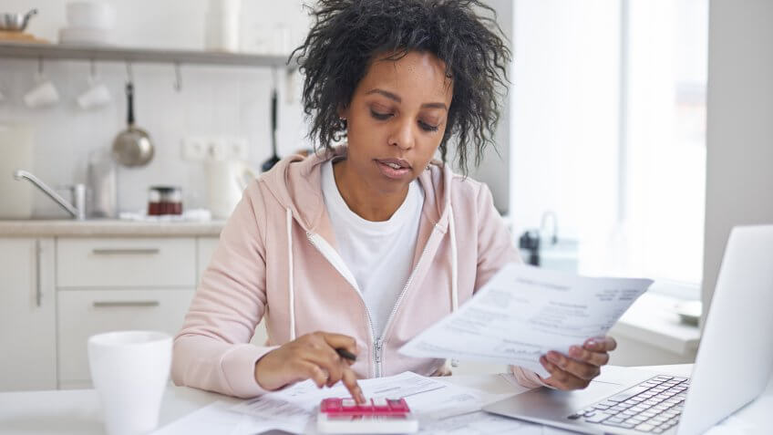 woman reviewing her billing statements and using calculator