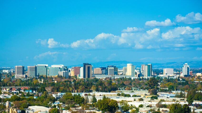 Vista of the San Jose skyline, with puffy clouds in the background and residential areas in the foreground.