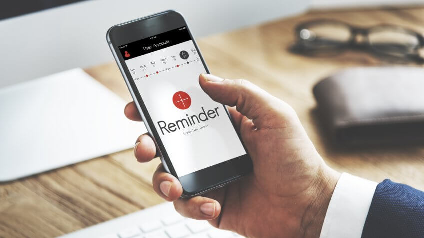 man using a reminder app on his smartphone at his desk