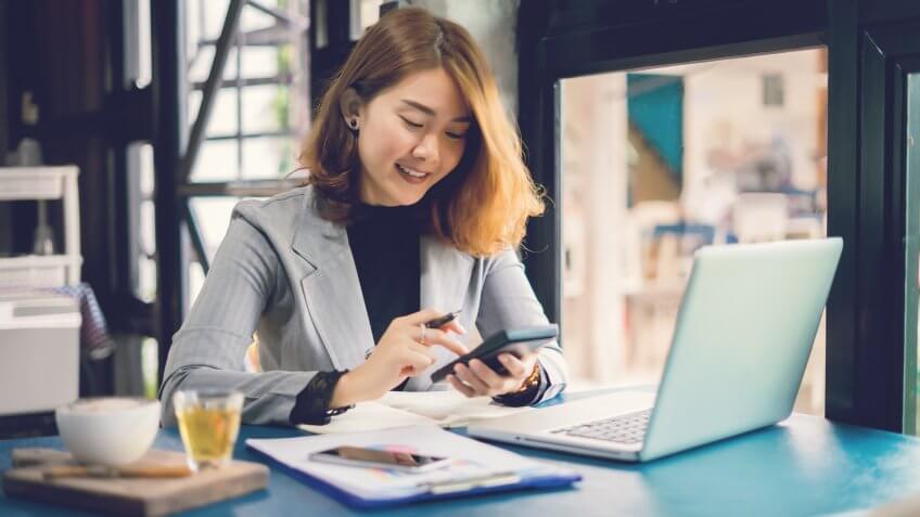 Smiling Young Businesswoman working with calculator, business document and laptop computer notebook,financial inspector and secretary making report,Internal Revenue Service checking document.