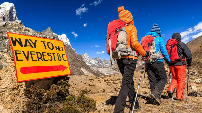 Group of three trekkers passing signpost "Way to Mount Everest Base Camp" - Mount Everest (Sagarmatha) National Park.