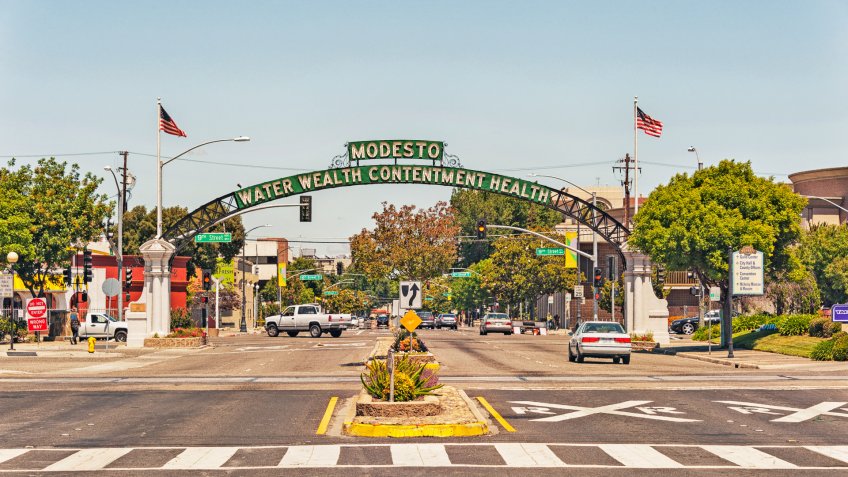Modesto, California, USA - May 15, 2016: This Arch with the name and mottos of the City Welcomes visitors to Modesto in the Central Valley of Northern California, the arch defines the feelings of the population that enjoys calling this home, the many signs and flags and vehicles make this entrance to this sections of this city very interesting and within close distance of historic site and museum this is also the setting for a very classic movie American Graffiti, areas of the city reflect the memories of the 1950's and on this May day it was very comfortable and interesting.