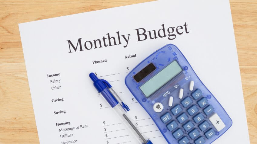 monthly budget sheet with pen and calculator