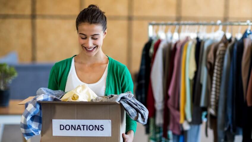 smiling woman holding a box of clothing donations