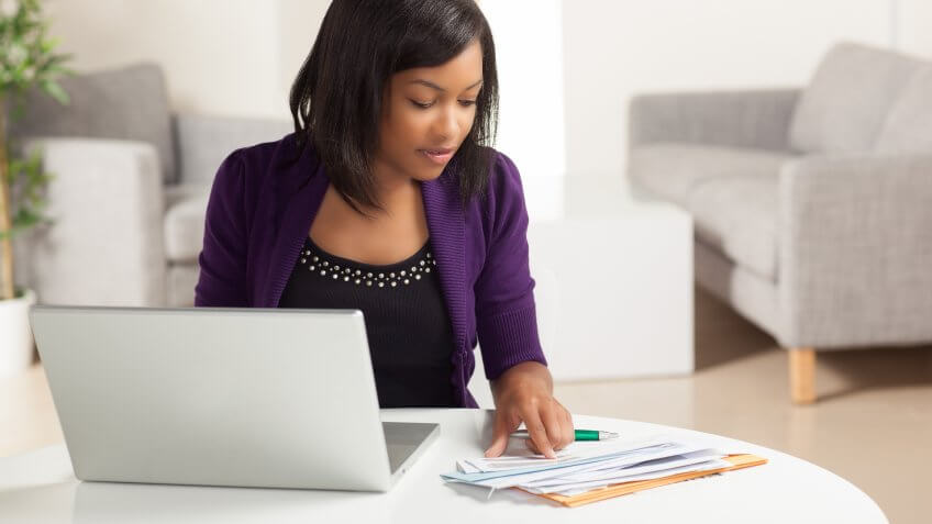 woman checking her billing statements at the desk in front of laptop